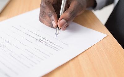 Hand signing a form with a pen